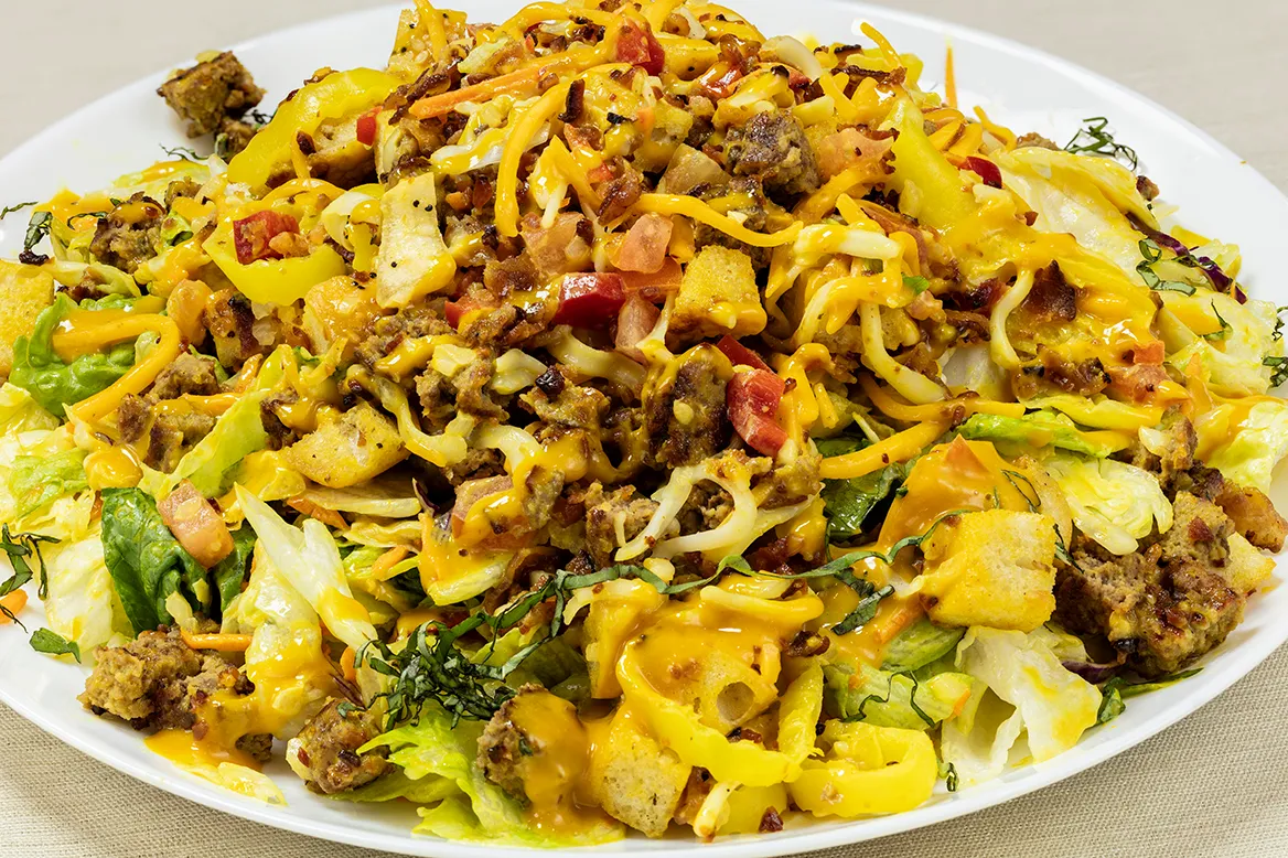 Bacon Cheeseburger Salad — chopped burger patty, bacon, diced tomatoes, mixed cheese, pepperoncini and croutons with golden BBQ dressing