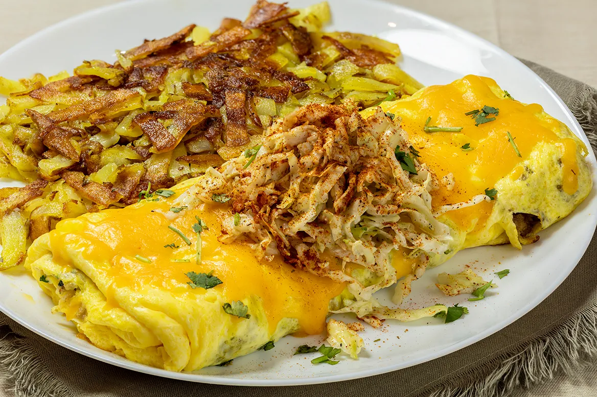 Turkey Taco Omelet — folded omelet with seasoned ground turkey and melted cheddar-jack cheese, topped with crunchy cabbage and chopped cilantro